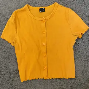 En gul t-shirt med knappar från Gina tricot. Stretchigt material så passar storlek M som en tajt magtröja. Kontakta privat för mått och fler bilder❤️