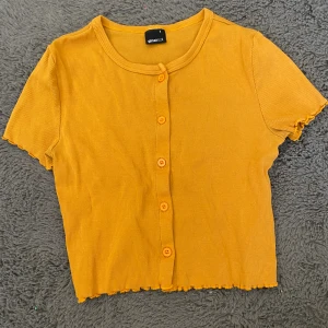 Gul t-shirt  - En gul t-shirt med knappar från Gina tricot. Stretchigt material så passar storlek M som en tajt magtröja. Kontakta privat för mått och fler bilder❤️