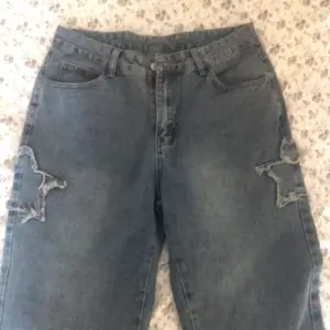 Skitcoola jeans med stjärnor på med lite tras på sidorna som ingår i designen☺️🎀använd gå gånger då den är för stor💕sitter som en M-L
