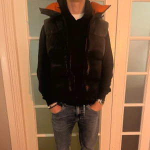 J.Lindberg väst -  Färg:Svart utsida, orange insida Storlek:Medium Skick:9/10 Nypris:4000 Mitt pris:1800 Modellens längd:180cm