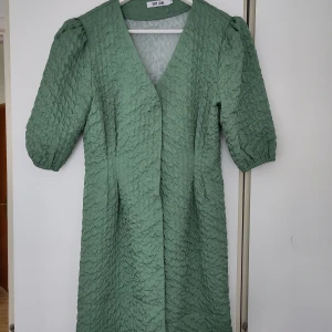 Fin klänning med puffärmar - Grön klänning med puffärmar, markerad midja och dolda knappar fram ☺️  Använd vitt ett tillfälle. Går till ovanför knäna 