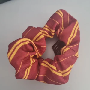 Scrunchie  - Säljer denna scrunchie med gryffindormönster då jag inte använder den längre. Säljer även matchande diadem. Kontakta innan köp eller vid frågor! Går att ändra/diskutera pris. 