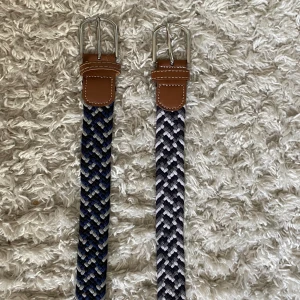 Flätade bälten - Två flätande bälten där ett är blått, svart och vitt, och det andra är  grått, svart och vitt. Båda är ifrån onewear och väldigt bra skick. 75 kr styck.
