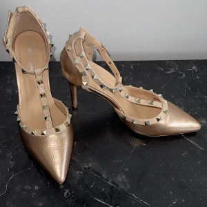 Beige klackar med nitar  - Superfina beige klackskor med nitar som tyvärr aldrig används. Passar storlek 39-40. 10 cm höga. Värda ca 1000kr. 