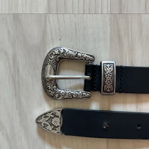 Zign Läder bälte - 99kr - Svart Zign läder bälte med graverat bältspänne och slut tipp. Storlek 85/34 med hål mellan 85 och 98, sista hålet är slaget med håltång.