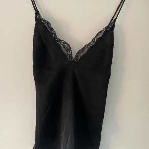 Svart Festtopp med spets från Nelly - Säljer detta perfekta svarta linnet från Nelly, en perfekt festtopp! Aldrig använt, så i mycket bra skick. Syns dåligt på bilden, men axelbanden är korsade på ryggen. För mer frågor skriv gärna privat🥰🫶🏼