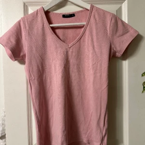 Basic t-shirt - V-ringad T-shirt i puder rosa. Stl. S