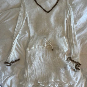 Genomskinlig vit klänning - Sheer klänning, vit med bronsdetaljer i storlek 36/small. Mycket fint skick, skulle va så fin med ett par bruna boots eller liknande! Skriv om du har några funderingar eller önskar fler bilder. 
