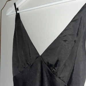Svart långklänning perfekt till nyår! - Superfin svart långklänning med v-ringning. I glansigt tyg. Köpt här på plick men tyvärr för kort för mig. (176cm)  Jättefint skick.  Skriv vid fler bilder eller intresse🖤