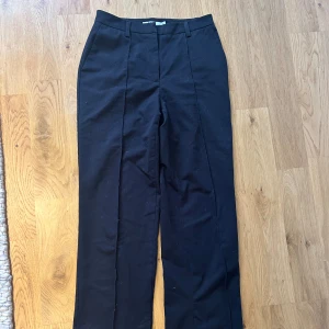 Kostymbyxa NA-KD högmidjad - Väldigt sköna och snygga kostymbyxor från NA-KD. Högmidjade i Strl 34. Tyvärr är dessa för stora i midjan för mig, därför säljer jag. Har en slits i nederkanten som faller fint över skor.