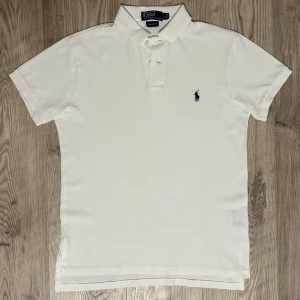 Polo piké  - Riktigt fin vit piké med mörkblå logga perfekt för sommarn. Helt ny