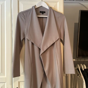 Trenchcoat  - Grå lite längre trenchcoat med skärp. Nyskick! 