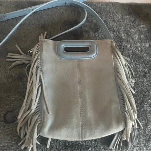 maje väska - ljusblå väska från maje i lilla storleken, välanvänd och är sliten i mockan på baksidan men fortfarande väldigt fin och det syns inte när den används! endast långa bandet finns kvar! tar bara swish