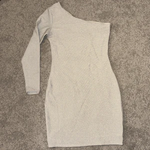 Glittrig Klänning  - Jättefin glittrig klänning från H&M som tyvärr blivit för liten för mig. Klänningen är one shoulder.