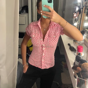 Rosa rutig kortärmad skjorta/ blus - Så söt rutig blus/ kortärmad skjorta. Man kan justera passformen där bak (på bild 2) och jag brukar alltid ha xs i kläder och den sitter så bra. 