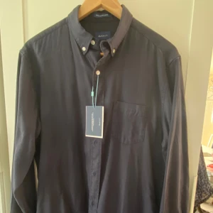 Gant skjorta - Marinblå skjorta från gant. Skjortan har aldrig använts pch har alla taggar kvar. Nypris:799 kr. Mitt pris: 349. Hör av er vid eventuella frågor eller vid behov av fler bilder