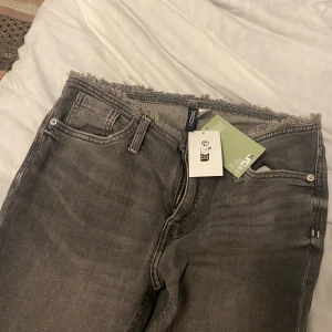 Jeans - Oanvända grå jeans från H&m lågmidjade och jättefin detalj vid midjan.