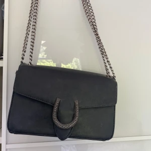 Svart väska - En svart väska med en ”hästsko” där man öppnar Man kan justera kedjan till hur man vill ha den, lång/kort Skitsnygg och ball