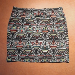 Mönstrad kjol från FS Sister - En färgglad kjol med geometriskt mönster i svart, vitt, rött, gult och grönt från FB Sister. Kjolen är kort och har en tight passform. Resårmidja. 37 på längden, 40 på bredden, stretchigt tyg. Storlek M. I princip oanvänd.