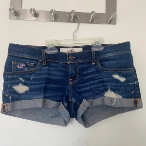 Hollister lågmidjade shorts, stl 26 - Lågmidjade shorts med hål över fickorna i fint skick!  Frakt tillkommer, men plagg som köps kan samfraktas!