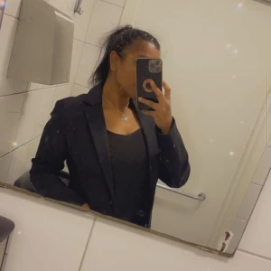 Svart kavaj från H&M - En elegant svart kavaj från H&M i storlek medium. Kavajen har en klassisk design med långa ärmar och två fickor framtill. Perfekt för både formella och semi-formella tillfällen.