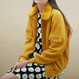 Senapsgul vår/höstjacka från the white pepper. - Som ny! Går att ta bort pälsimitationen på kragen. En liten knapp till "pälskragen" fattas men inget som syns eller förstör funktionen. Två fickor med dragkedja på vardera sida samt en ficka med knapp på vänster arm. Passar både dam och herr.  