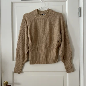 Stickad tröja från Gina - Stickad tröja i beige/ljus brun från Gina Tricot i storlek S. Ballongärmar och sitter åt i midjan nedtill. Stretchigt material. Använd men i fint skick. Bara att fråga om det är något du undrar! Kan mötas på Järntorget i Göteborg eller skicka, köpare