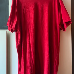 Röd T-shirt  - Tröja köpt secondhand, XL i storlek. Aldrig använt sen den köptes, inga tecken på användning. Själv tycker jag att den är normal i storlek. Finns på flera sidor. 