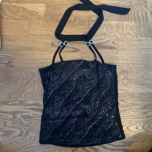 Svart festtopp - Svart glittrig festtopp som knyts i nacken🙌🏻 Väldigt stretchigt mjukt material och bra skick ❤️ Skriv vid frågor eller om fler bilder