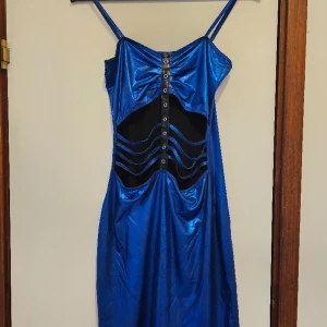 Blåmetallic klänning - Beskrivning: Blåmetallic klänning med snörningsdetalj på framsidan. Märke:  Storlek: Small Skick: Använd med i bra skick Material:   Nakenkatt finns i hemmet