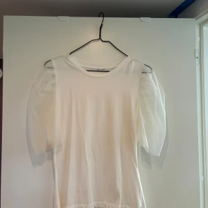 Vit tröja med en volang likande ärm - Inte använd så mycket Har inga skavanker  Skönt material 
