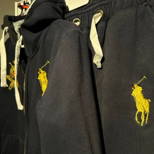 Mjukisset från Ralp Lauren - Ett marinblått/svart Mjukisset från Ralp Lauren. Dragkedjan på hoodien kärvar lite 