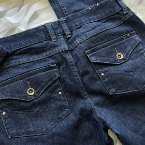 Low waisted mörkblåa jeans Y2K/Vintage  - Vintage lågmidjade jeans från Veromoda. Storlek 40. Bakfickorna har en unik design. Midjemått = 83cm, innerbensmått = 83cm , Ytterbensmått = 105cm  