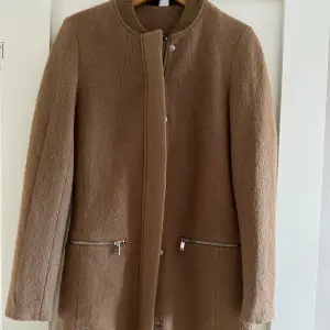 Brun jacka/kappa med 40% ull från H&M storlek 36. Aldrig använd, endast provad. Tyvärr för liten för mig. Perfekt vår/höstjacka!