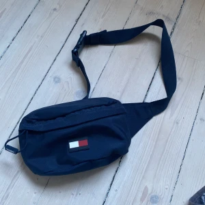 Tommy Hilfiger midjeväska  - Tja, säljer denna sköna midjeväskan från Tommy Hilfiger då den inte använts på länge. 10/10 cond. Hör av er för fler frågor och funderingar. Frakt står köparen för. 