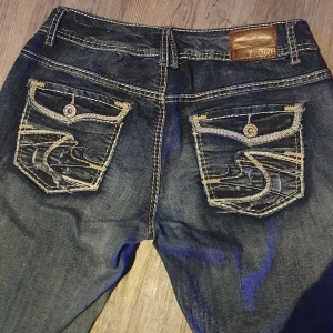Detaljrika mörkblåa bellbottom jeans - Snygga bellbottoms, tyvärr är de för stora för mig :,). Knappen hade gått av men har ersatt det med en annan jeansknapp som man ser på sista bilden. annars är de helt felfria 😁 