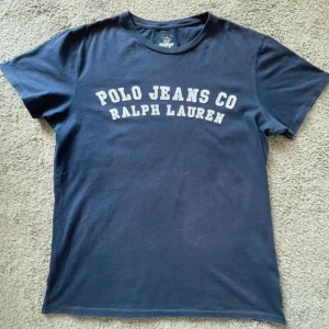 Ralph Lauren T-shirt - Tja, säljer min Ralph Lauren t shirt som jag växt ur och inte använder mer. Denna t shirt passar till mycket och perfekt nu till sommaren. Skicket på t shirten är väldigt bra och inte använd mycket skulle säga skicket är 9/10. Kontakta mig vid frågor