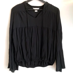 Svart volang blus, stl 36/38 S, trumpetärm, bohemisk, boho, enfärgad, luftig, v-ringad - Svart blus med volanger. Utställd ärm, resår i nederkanten. Mått får ej plats - fråga gärna!