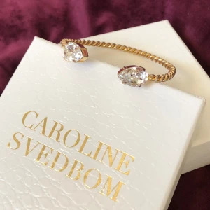 Caroline Svedbom Guld armband  - Använt och lite skavt, syns inte så mycket  Kan skicka mer bilder vid intresse :) där av billigt pris Klassisk modell med guld och vit Sten  Byter gärna mot silver eller guld med rosa/turkos/gul 