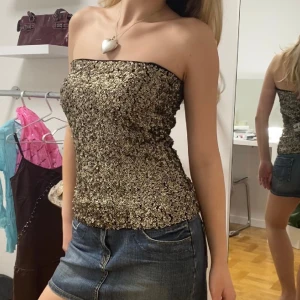 Tubtopp med paljetter - Tubtopp med champagne/guldfärgade paljetter från Vero Moda. Så sjukt snygg men känner aldrig att jag passar i tubtoppar tyvärr. Strl M men har du större byst borde den passa en S lika bra utan att glida ner.🖤