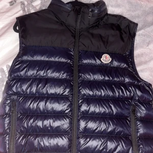 Moncler väst - Äkta  Blå/Svart Moncler väst med inbyggd luva. knappt använd 10/10 skick. kvitto finns! OBS! vi står ej för frakten Pris kan diskuteras!