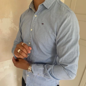 Tommy Hilfiger skjorta - En ljusblå Tommy Hilfiger skjorta i mycket bra och fint skick. Nästan aldrig använd och ser ny ut. 150kr + frakt