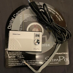 Camera - Praktica SlimPix digitalkamera. Kameran är liten och kompakt, perfekt för att ta med sig på resan. Den har en inbyggd blixt och kan ta bilder i hög upplösning. Kameran levereras med en USB-kabel laddare batteri i och en CD-skiva med programvara.