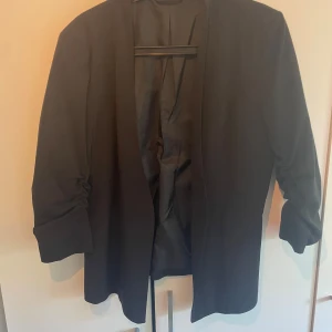 Kavaj  - Svart kavaj med rynkad trekvartsärm i storlek L.  Vadderade axlar.  Från Vila