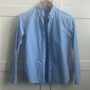 Snygg Skjorta Tommy Hilfiger - Orginalskjorta från Tommy Hilfiger. Använd 2 ggr och tvättad 1 gång. Nyskick. Somrig snygg blå färg. Nypris 899:- Passar perfekt på en normalväxt 11-13 åring. 