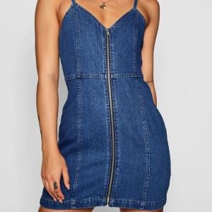 Denimdress  - En denimdress från Boohoo med dragkedja framtill. Klänningen har smala axelband och en tajt passform 🌷 säljer då den blivit för liten~ kan MÖTAS upp i sthlm också!