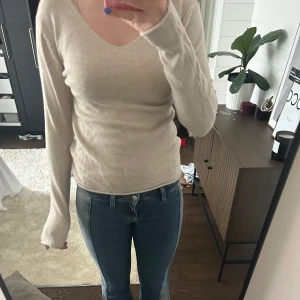 Beige långärmad tröja med v-ringning - Säljer en enkel och stilren beige långärmad tröja med v-ringad hals. Tröjan har en smal passform och är perfekt att matcha med jeans eller kjol. Supermjuk och skön att ha på sig. Aldrig använd 