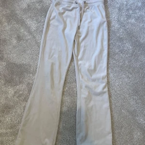 Beige mjukisbyxor från Gina Tricot - Beiga mjukisbyxor från Gina Tricot med raka ben och dragsko i midjan. Byxorna har bakfickor och är tillverkade i ett mjukt material som passar perfekt för en avslappnad stil. Det är ett hål på fickan men går att sy ihop