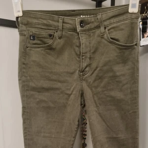 Olivgröna shaping jeans - Säljer ett par olivgröna shaping jeans med skinny fit och regular waist. Byxorna har klassisk femficksdesign och är tillverkade i stretchig denim för en bekväm passform.