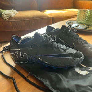 Vapor 15 Elite ag - Svarta vapor 15 i väldigt bra skick förutom liten spricka i sulan. Köpt på unisport för ett tag sen men knappt använda för de var för små. Kan gå ner i pris vid smidig affär!🙌🏽🙌🏽